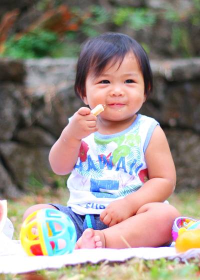 Young child eating a snack outdoors.