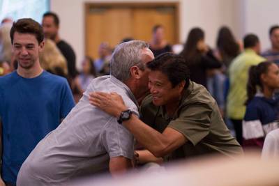 Community members greeting each other at a gathering.